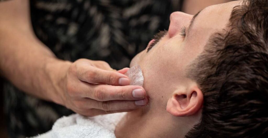 Foto de un hombre siendo exfoliado con una piedra de alumbre
